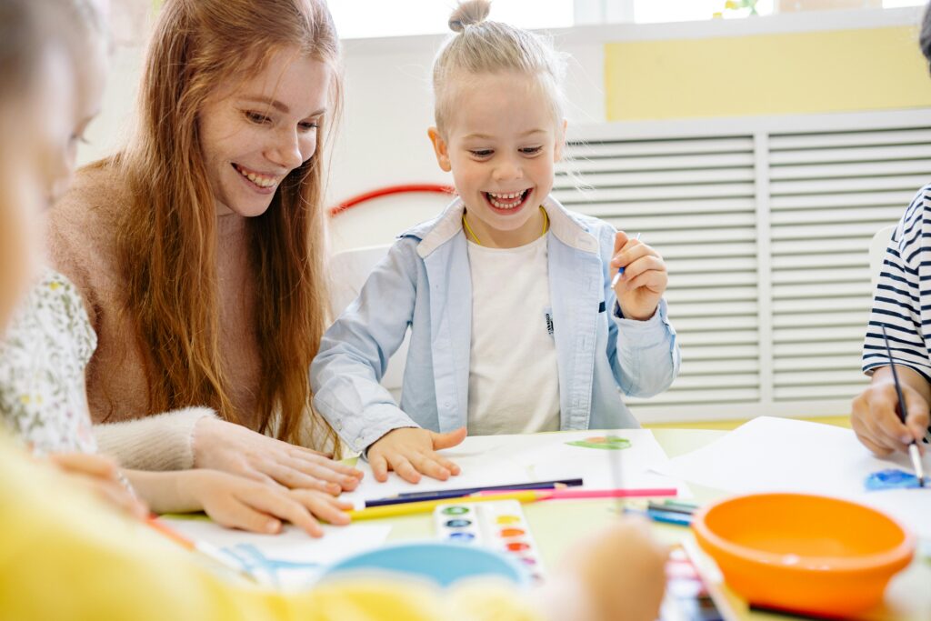 Happy children and teacher enjoying a creative arts and crafts session in a cheerful classroom setting.